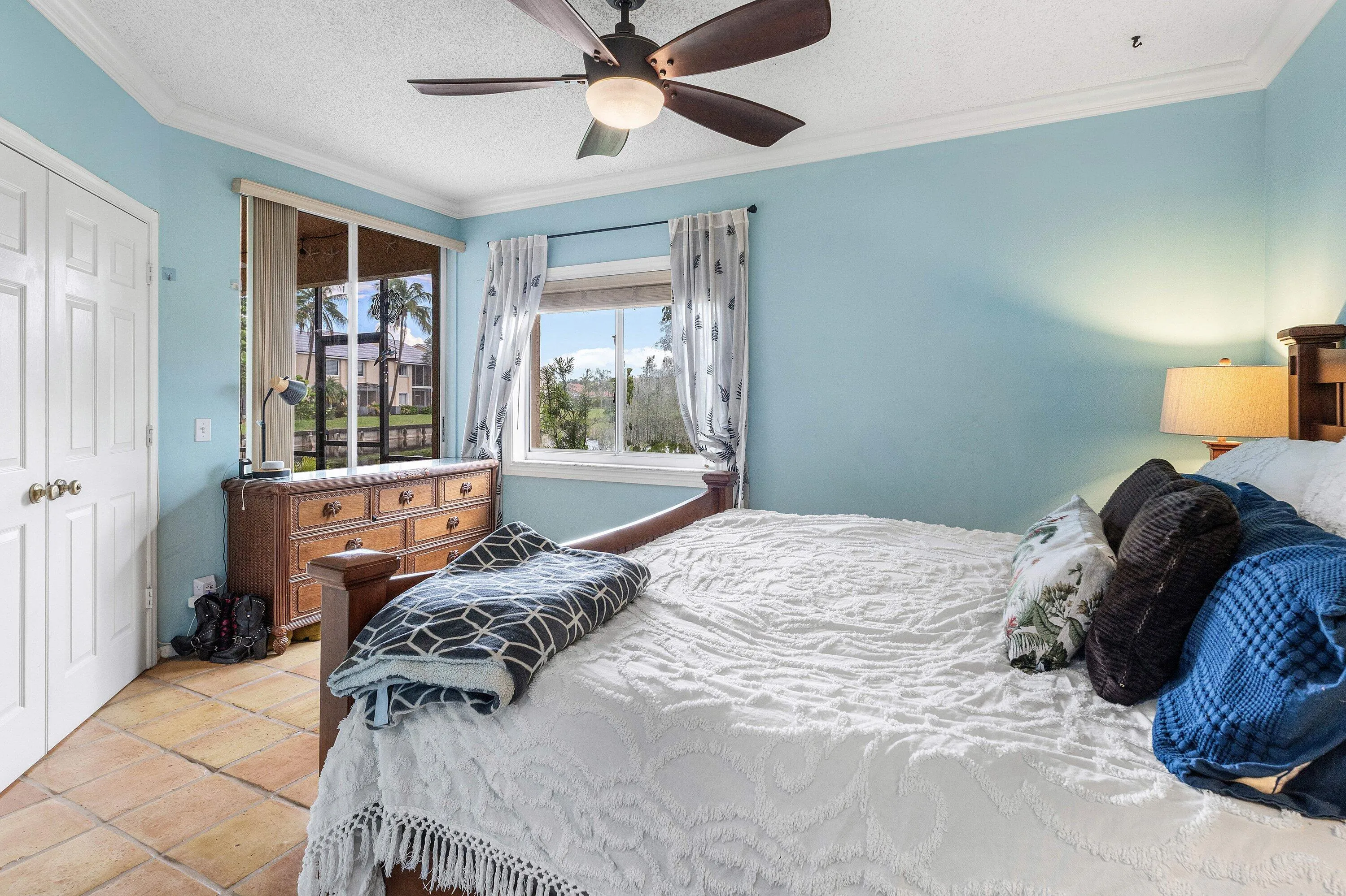 Bedroom featuring terracotta tile flooring, dual windows, and a ceiling fan