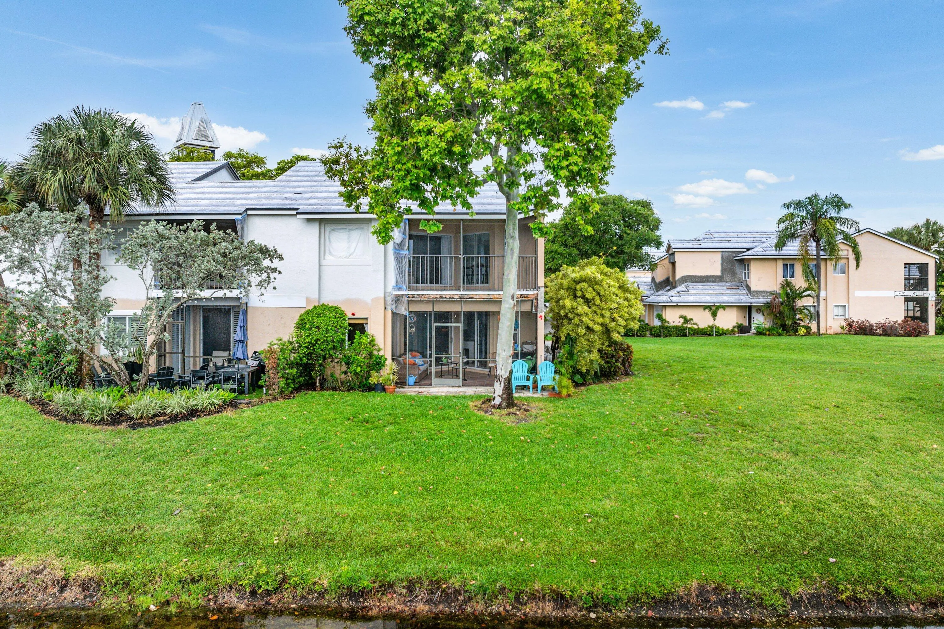 Expansive green lawn with established trees and shrubs bordering a water feature