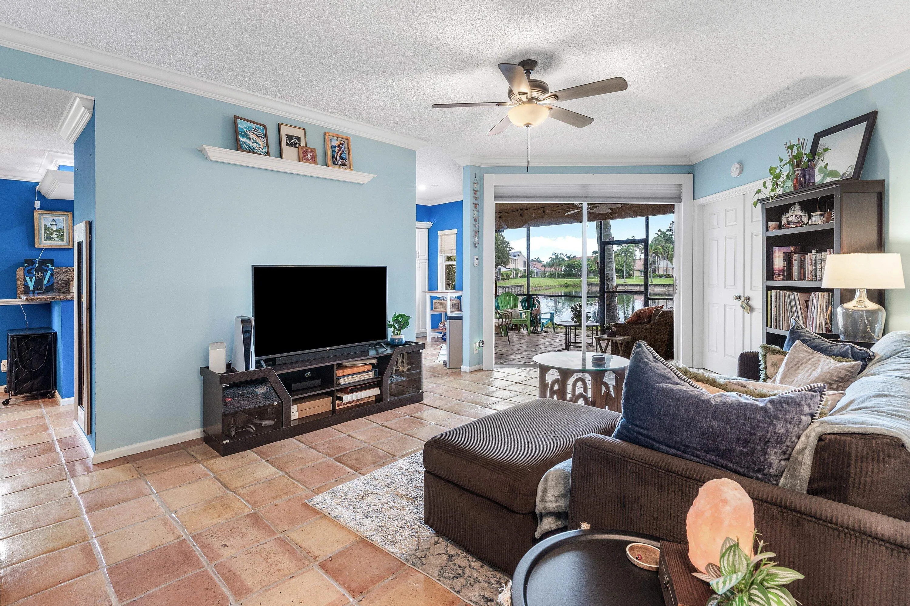 Spacious living area featuring tile flooring, crown molding, and a ceiling fan