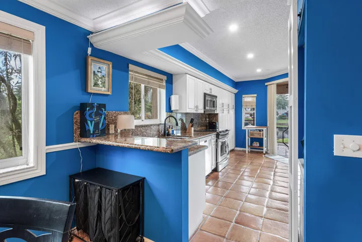 Kitchen featuring white cabinetry, granite countertops, stainless steel appliances, and tile flooring