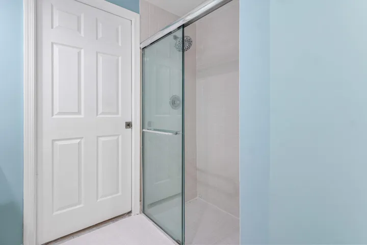 Shower enclosure with clear glass sliding door, tiled walls, and a white showerhead