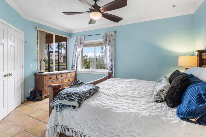 Bedroom featuring terracotta tile flooring, dual windows, and a ceiling fan