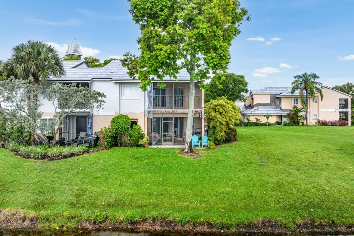 Expansive green lawn with established trees and shrubs bordering a water feature