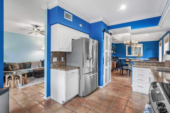 Kitchen featuring terra cotta flooring, white cabinetry, granite countertops, and stainless steel appliances