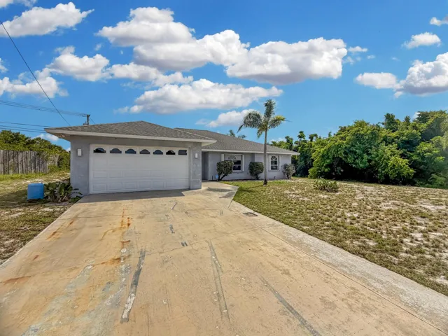 Ranch-style exterior featuring a stucco finish, attached garage with decorative windows, and a gray shingle roof