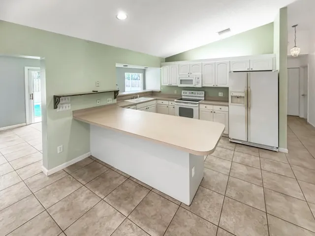 Kitchen featuring white cabinetry, light-toned countertops, and a central peninsula