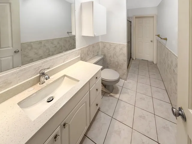 Bathroom vanity featuring an integrated sink with a chrome faucet, a light-toned countertop, and white cabinetry