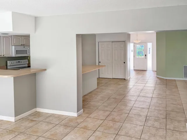 Open-concept interior featuring light tile flooring and a kitchen pass-through with a breakfast bar