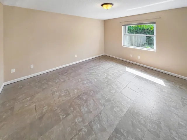 Spacious room featuring light-toned walls, a single window, and a ceiling-mounted light fixture
