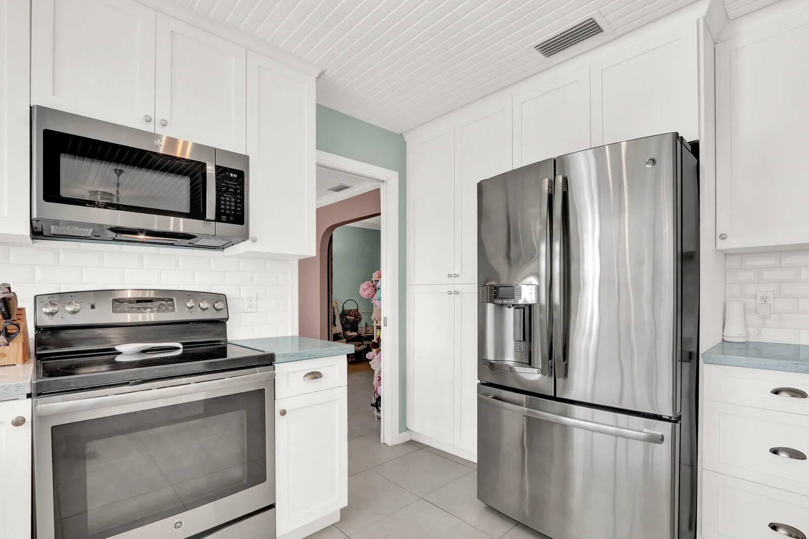 Kitchen featuring white shaker-style cabinetry, stainless steel appliances, subway tile backsplash, and light blue countertops