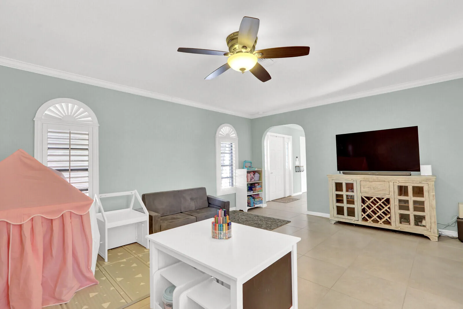 Spacious room featuring tile flooring, light-toned walls, and white crown molding