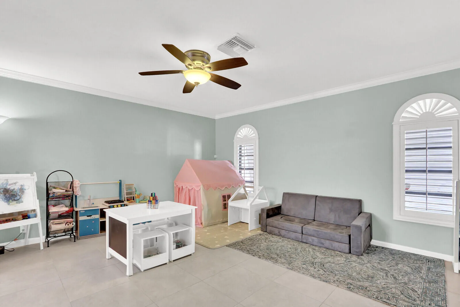 Spacious room featuring light-colored walls, crown molding, and tiled flooring