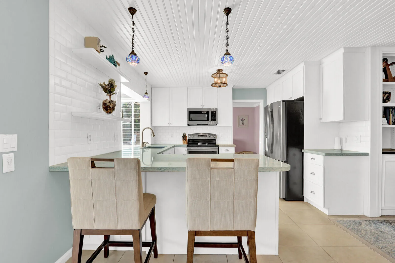 Kitchen featuring a breakfast bar with stone-finish countertop, white cabinetry, stainless steel appliances, and a plank ceiling