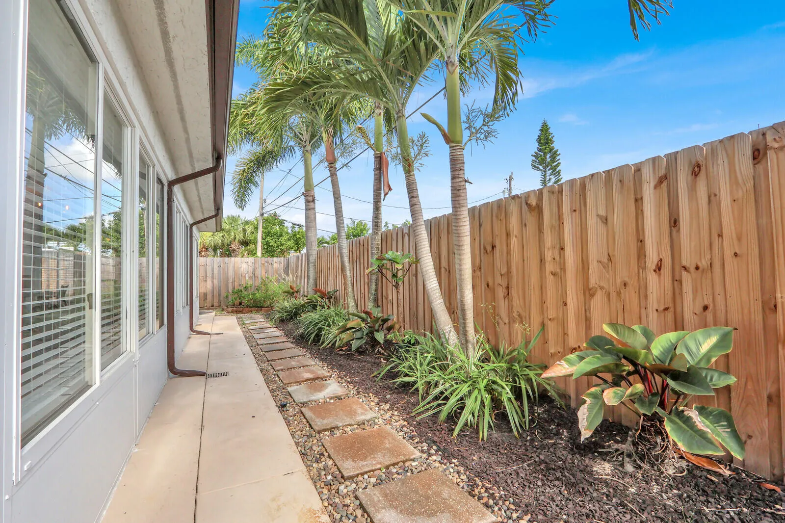 Rear exterior with a concrete pathway leading to stepping stones set in gravel and mulch