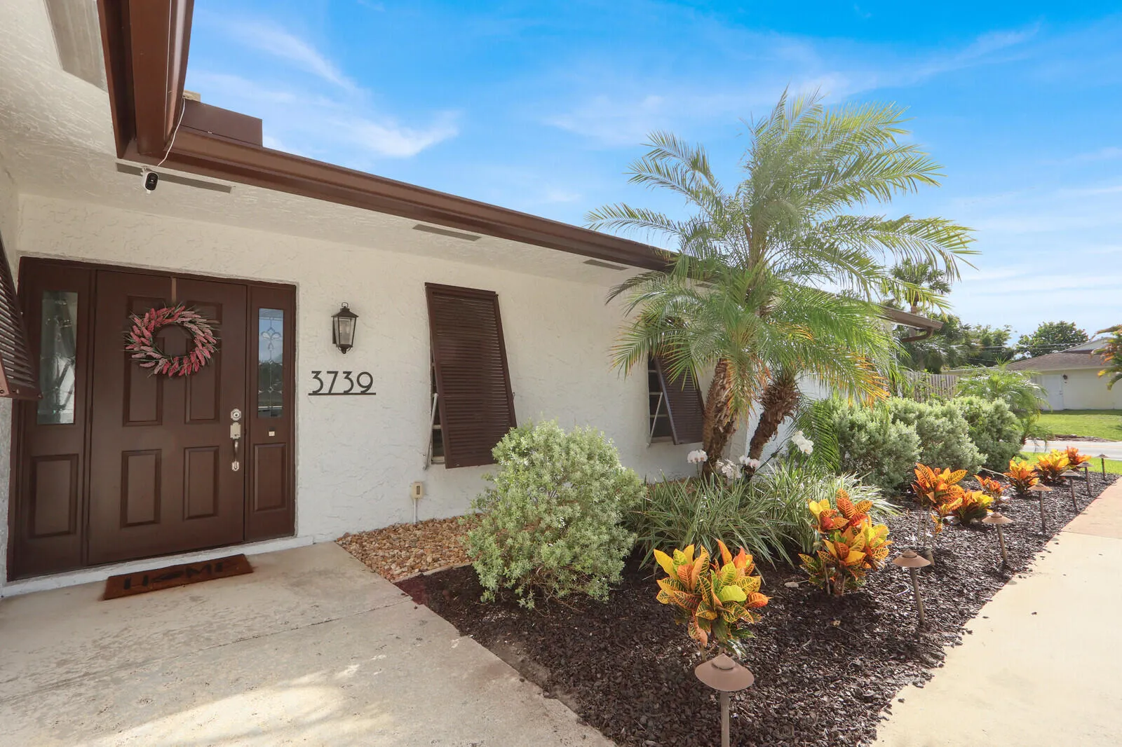 Front exterior showcasing a dual entry door with sidelights, decorative house numbers, and a lantern-style sconce