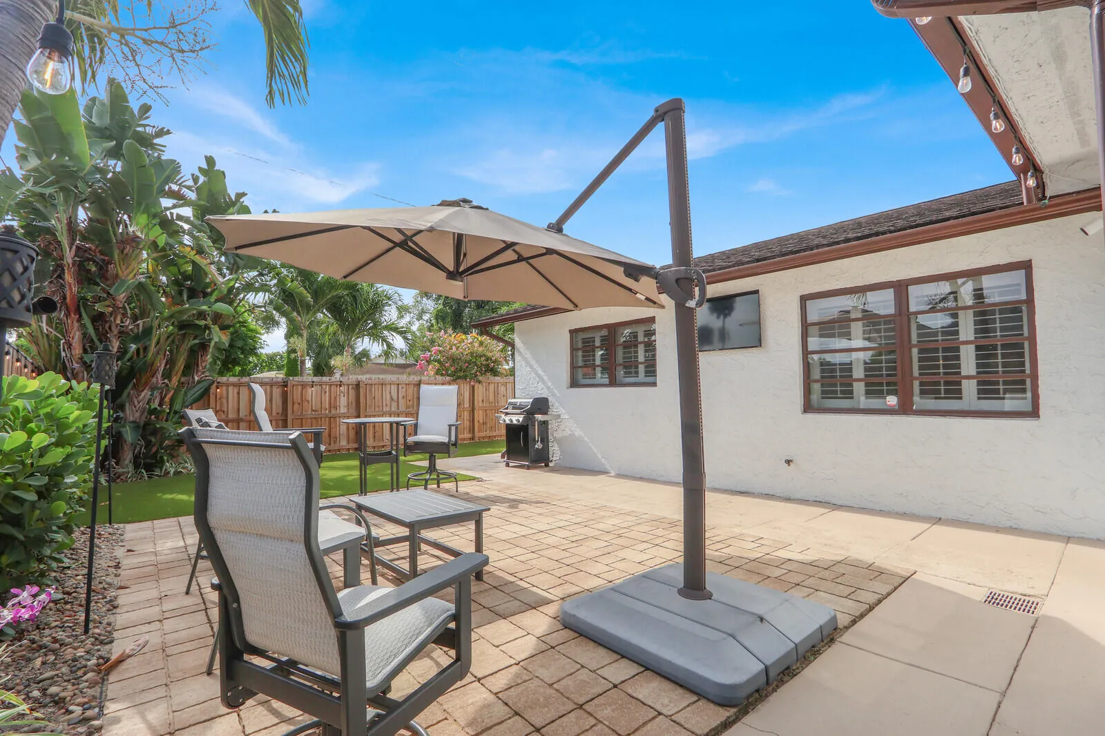 Expansive paver patio with a white stucco exterior and brown trim