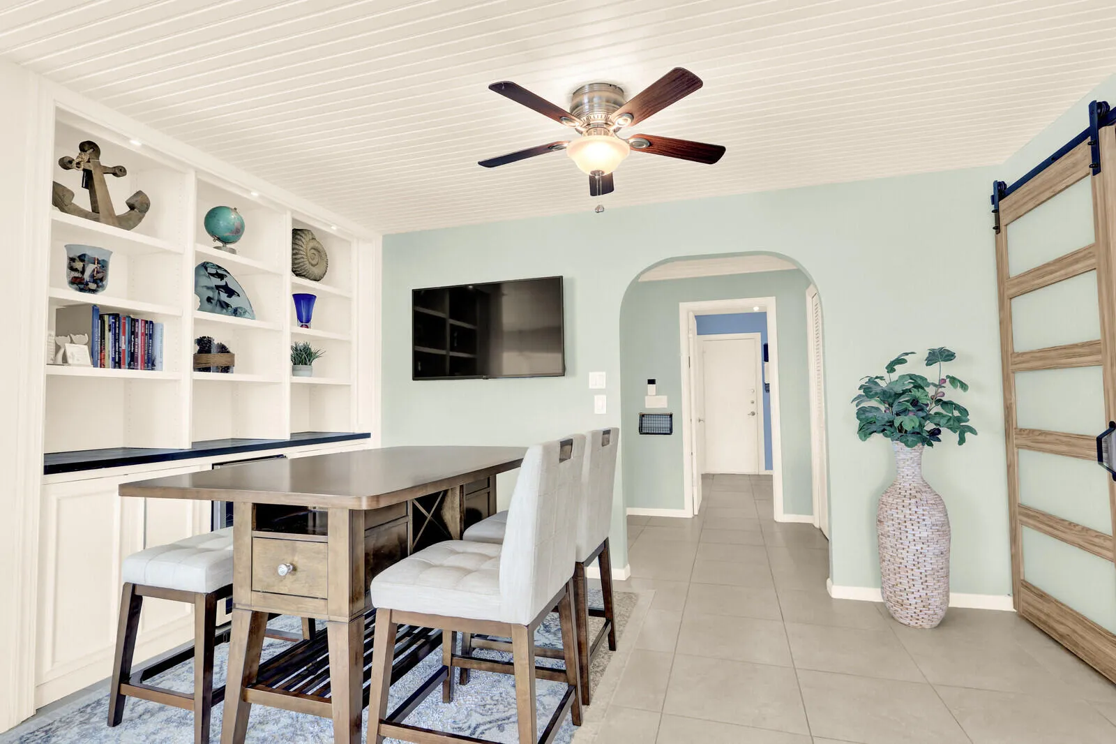 Built-in white cabinetry with open shelving, an arched doorway, and light-colored tile flooring