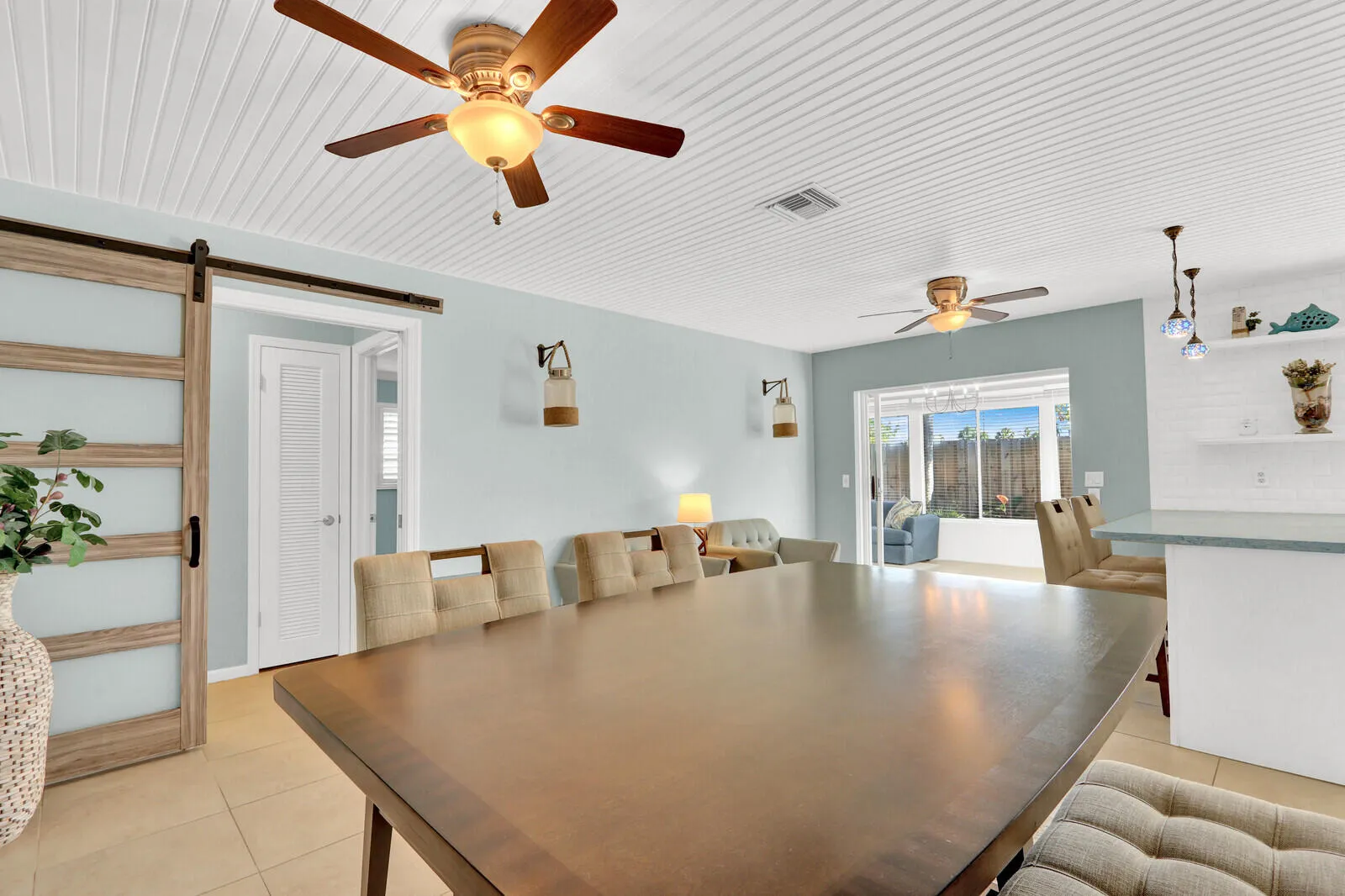 Spacious dining area featuring neutral tile flooring and a beadboard ceiling