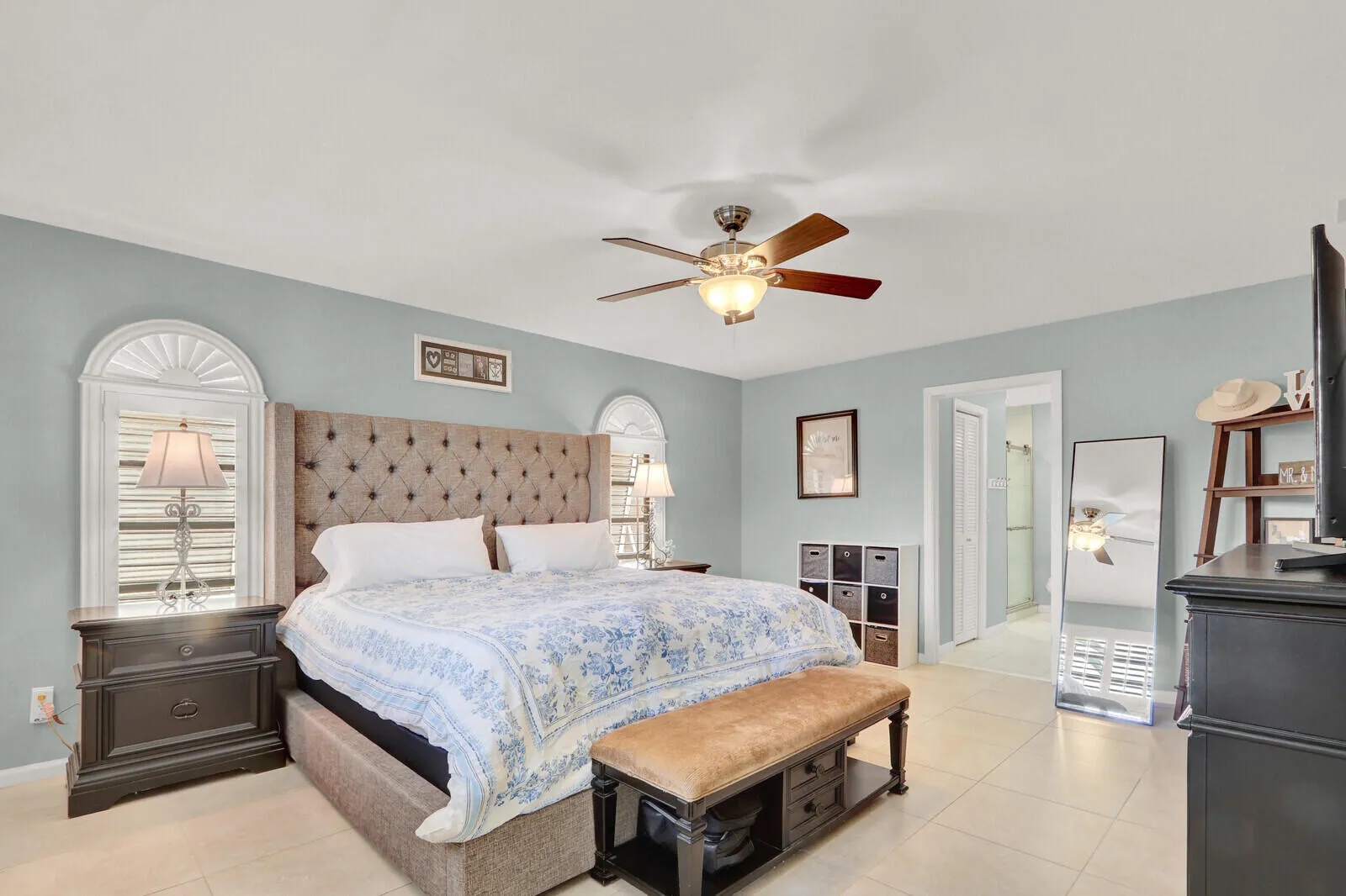 Spacious room featuring light-toned tile flooring, light blue walls, and a ceiling fan with integrated lighting