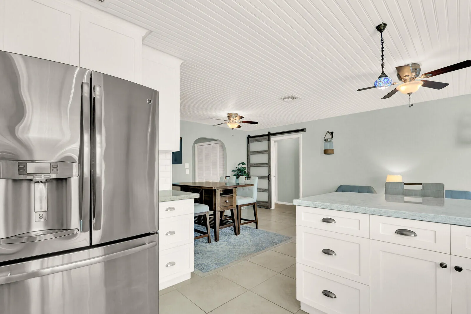 Kitchen featuring a stainless steel refrigerator, white cabinetry, and light-toned countertops