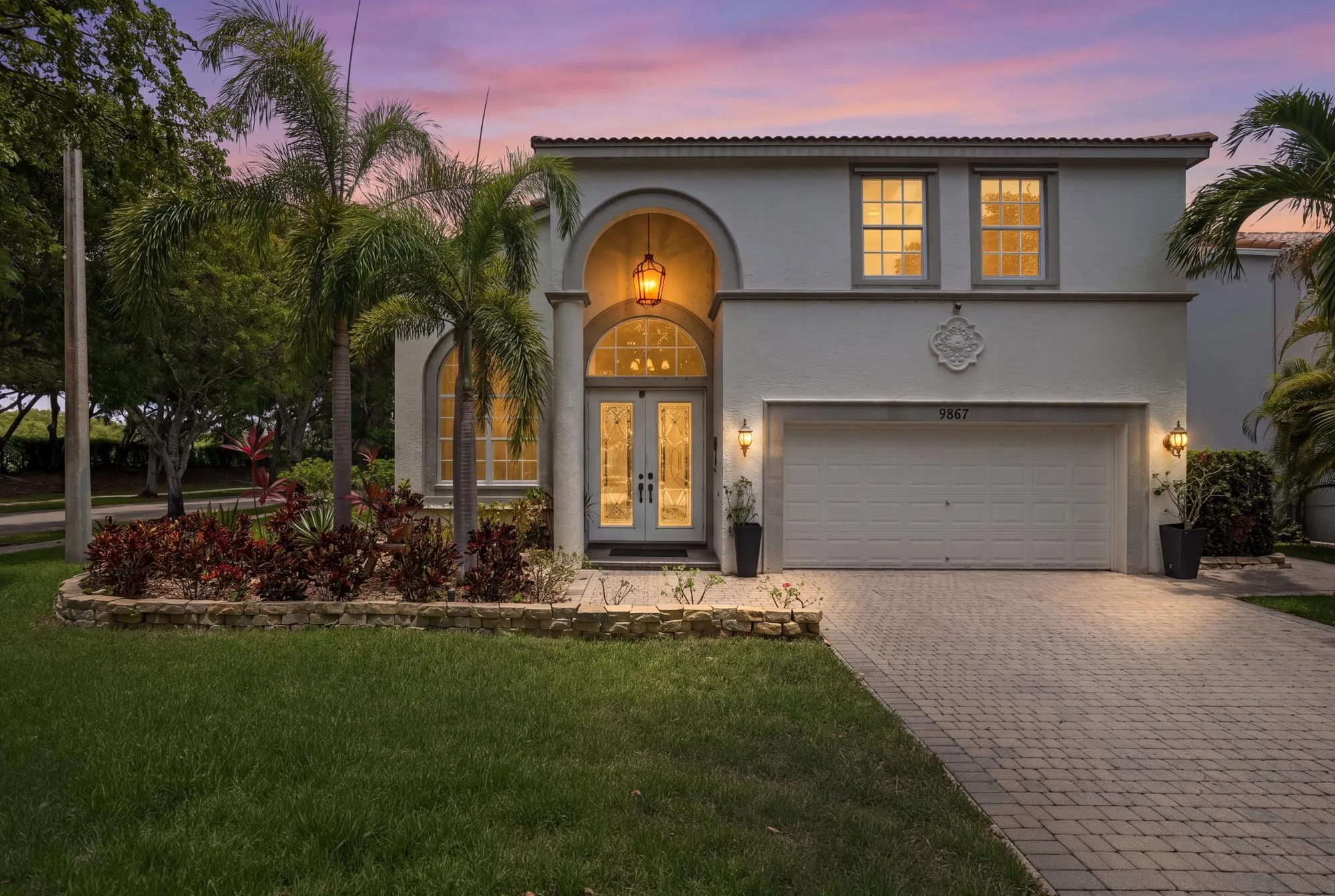 Stucco exterior residence featuring an arched portico entry with double glass panel doors