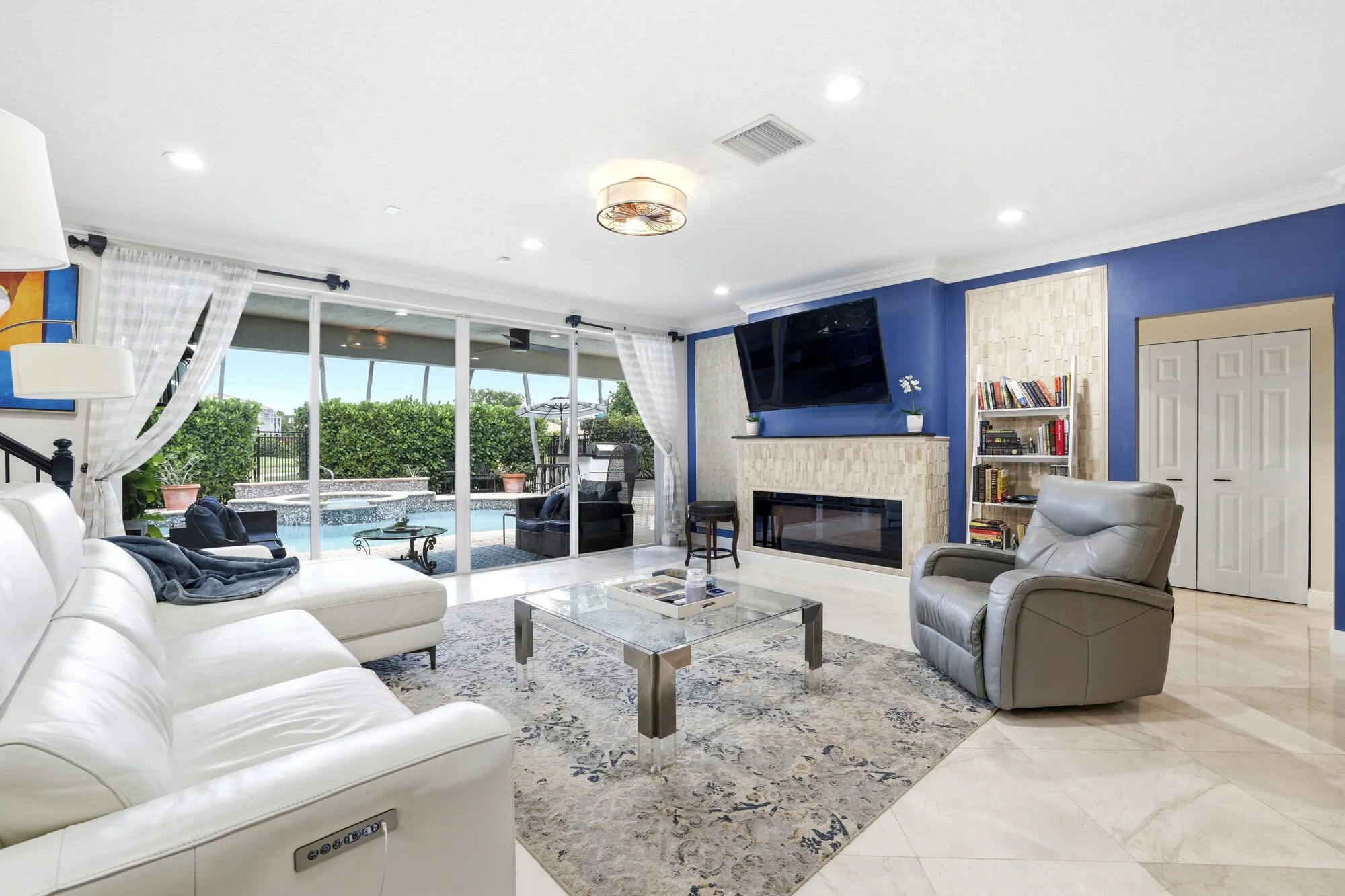 Spacious living area featuring large format tile flooring, crown molding, and recessed lighting