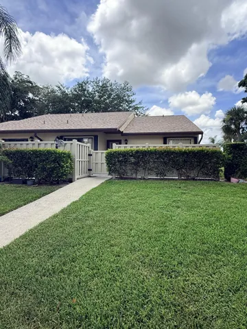 Tan exterior with a brown shingle roof and a front lawn