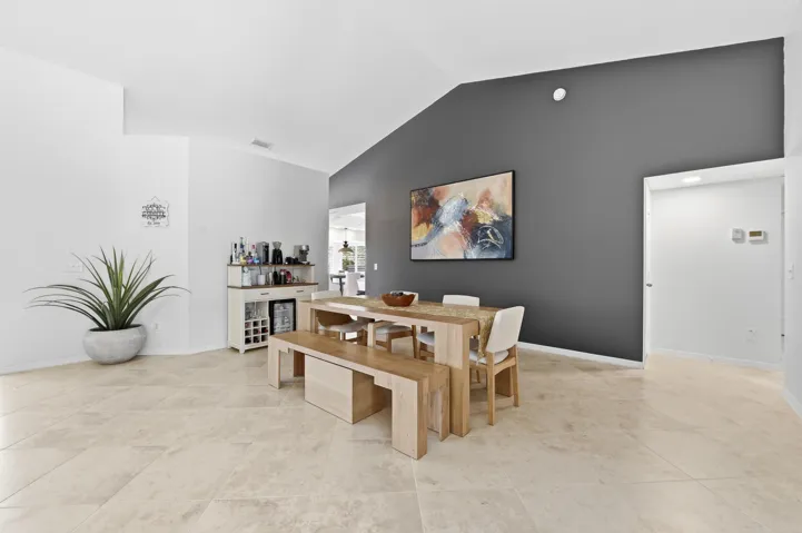 Vaulted ceilings in an open-concept room featuring light-toned tile flooring