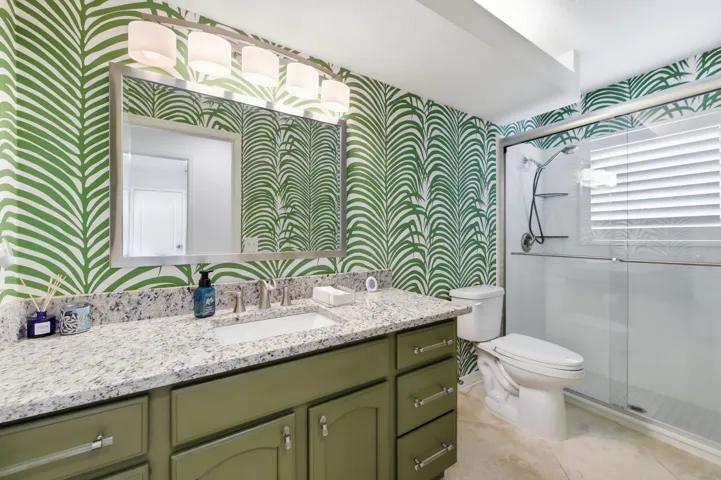 Bathroom featuring a single vanity with a granite-style countertop, undermount sink, and brushed nickel faucet