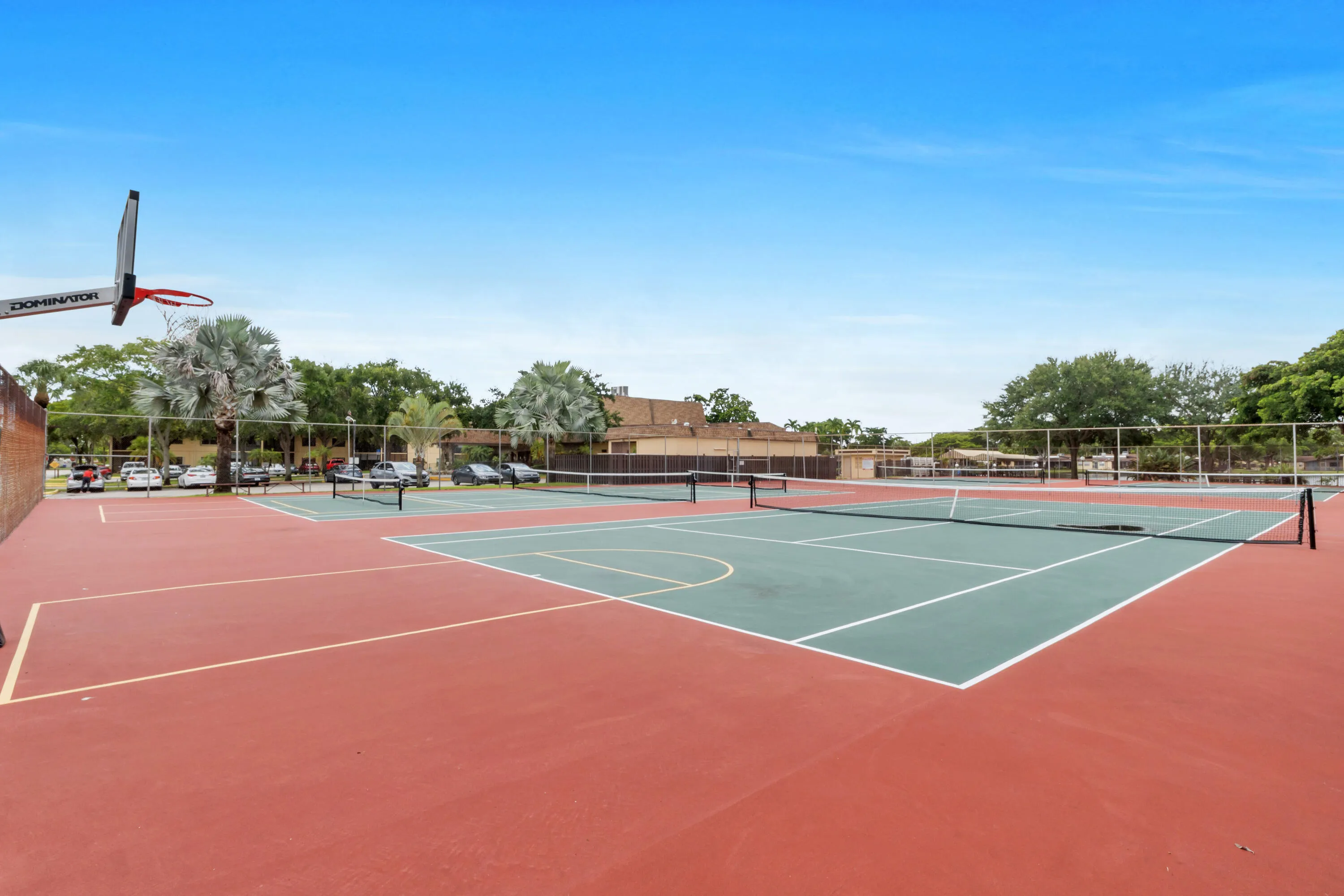 Multi-sport court featuring dedicated tennis courts, a basketball hoop, and two painted pickleball court lines and nets.