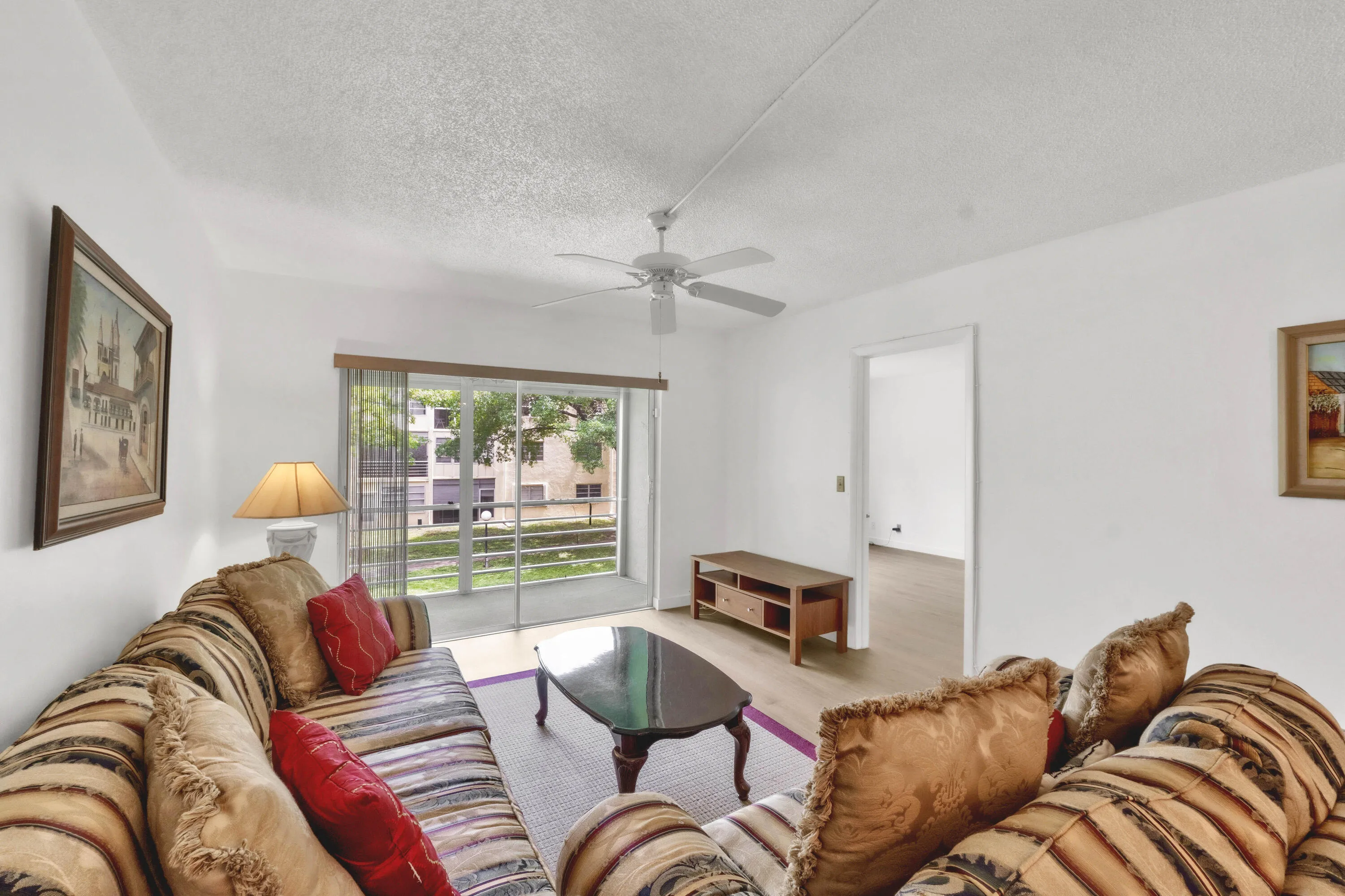 Living area opens to the lanai via a sliding glass door adorned with vertical blinds.