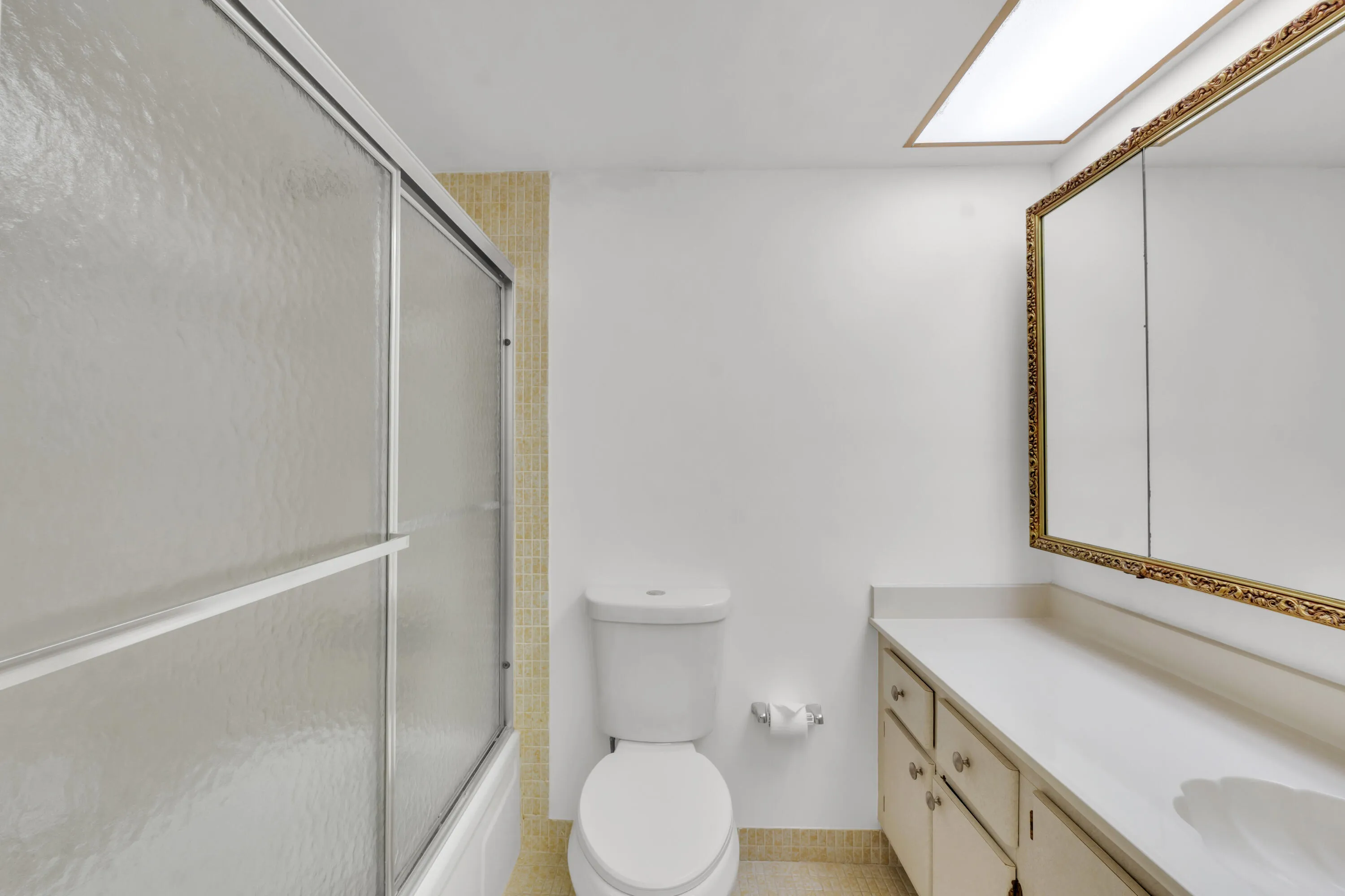 Primary bathroom featuring a shower-tub combination with sliding frosted glass doors.