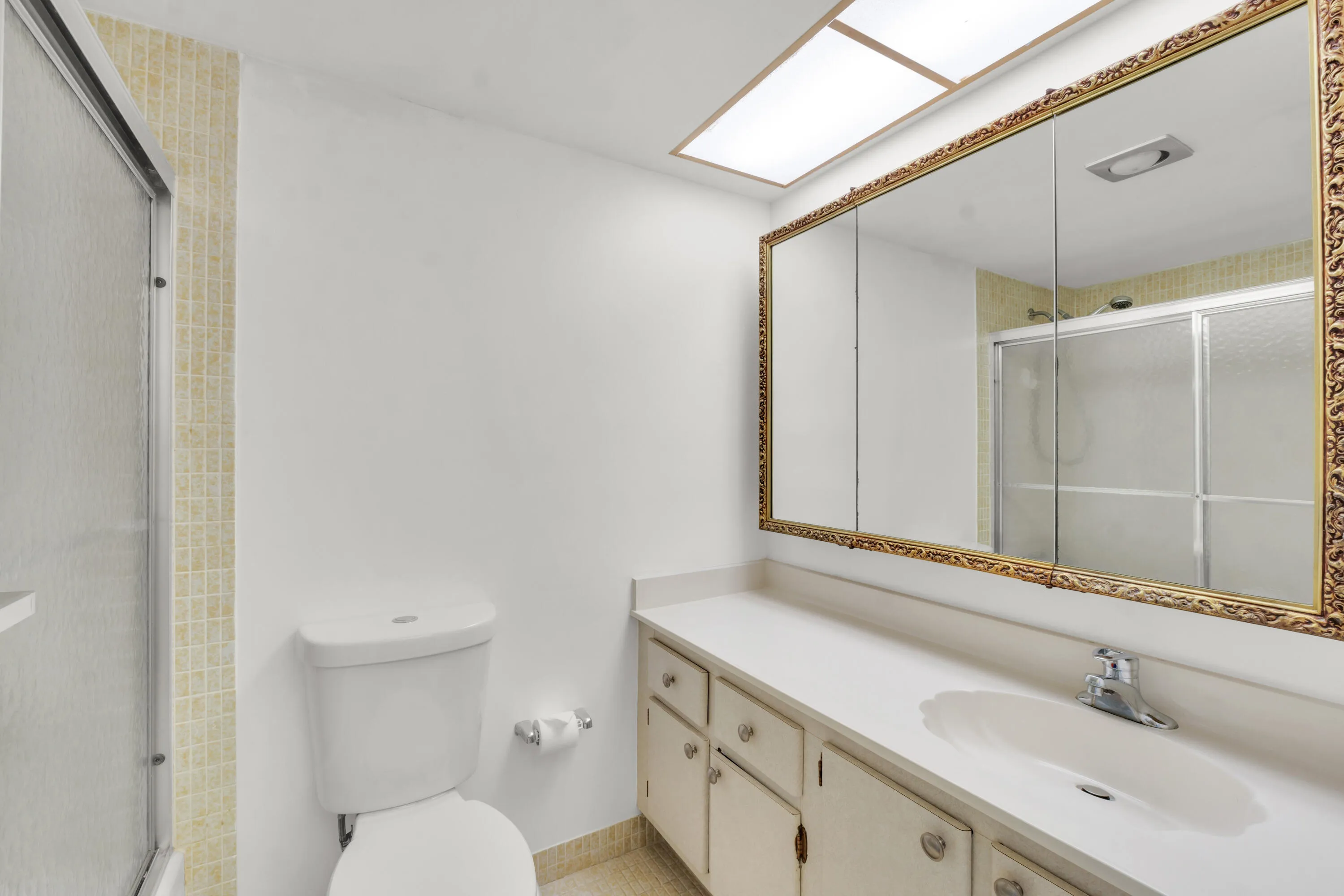 Primary bathroom featuring a shower-tub combination with sliding frosted glass doors.