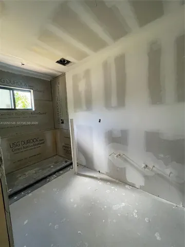 Interior space featuring unpainted drywall, cement board wall backing, a single window, and plumbing rough-ins