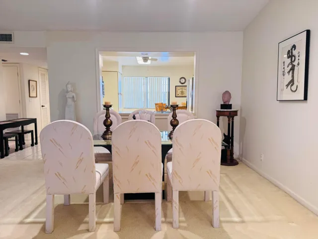 Dining area with neutral carpeting and a pass-through opening to an additional room