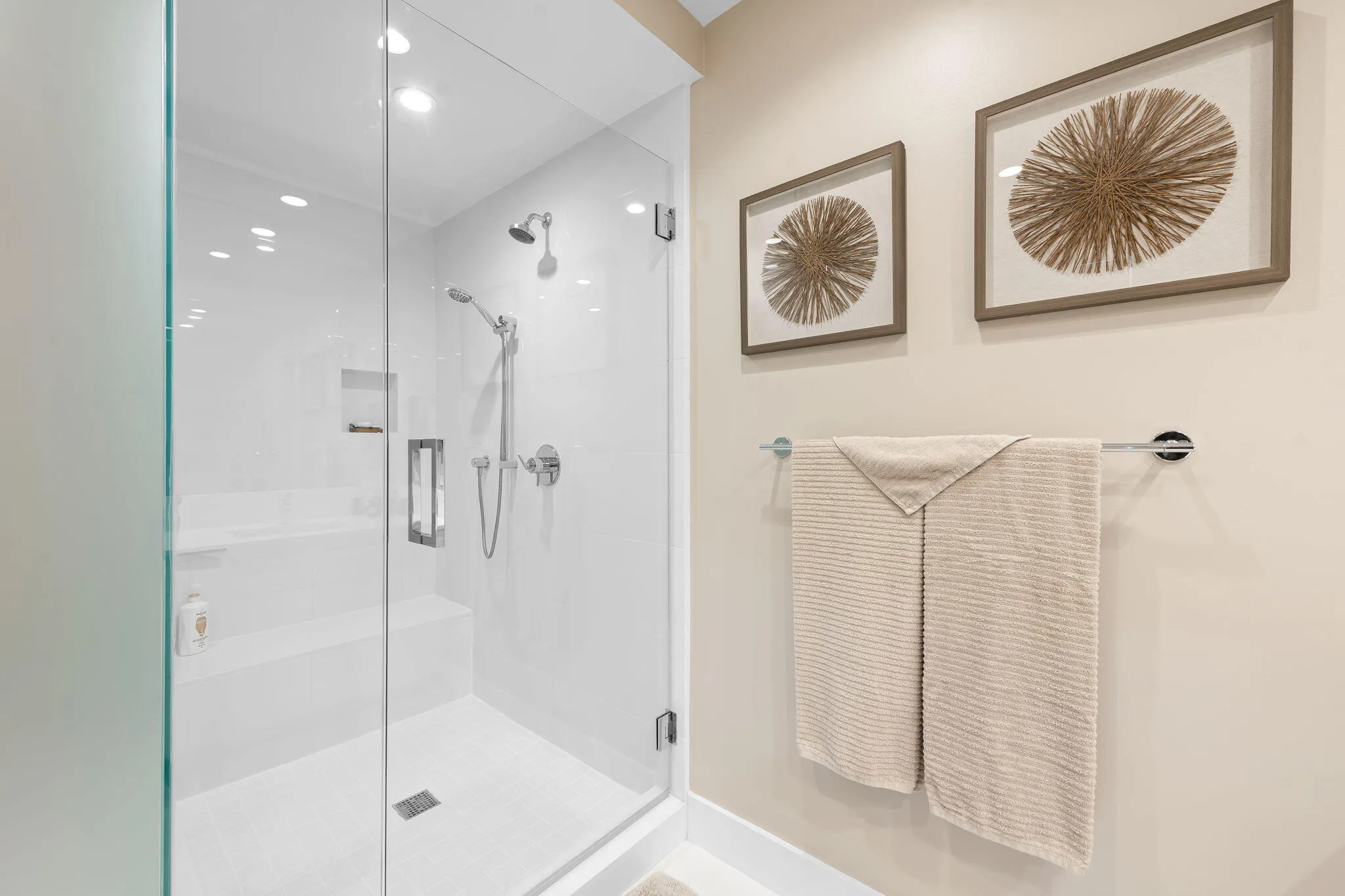 Glass-enclosed shower featuring a built-in bench, recessed shelf, and dual showerheads