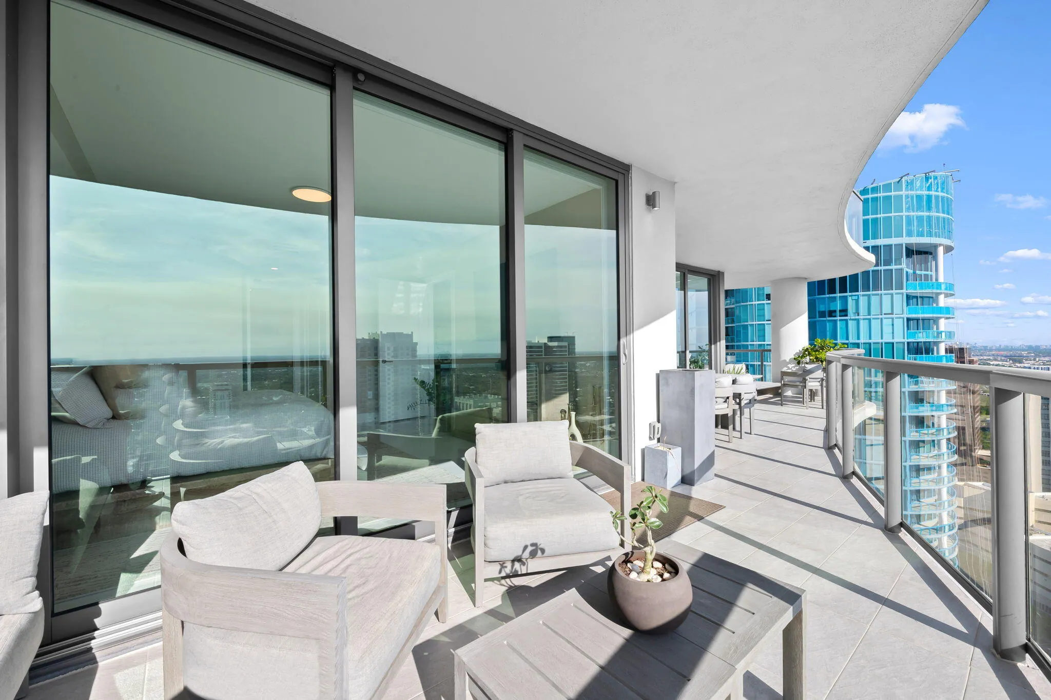 Expansive private balcony featuring glass railings, a curved ceiling, and light-tone tile flooring