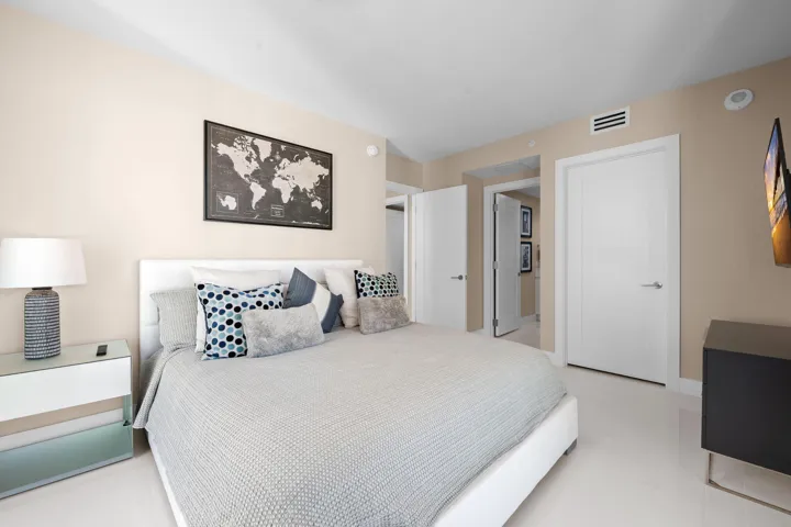 Neutral-toned bedroom featuring crisp white doors with brushed chrome hardware, recessed lighting, and light-colored flooring