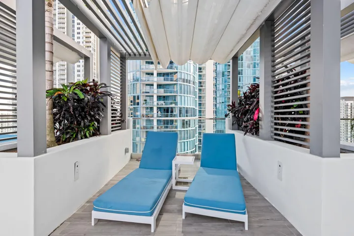 Outdoor patio area featuring a slatted pergola, retractable overhead canopy, and built-in planters with dense foliage