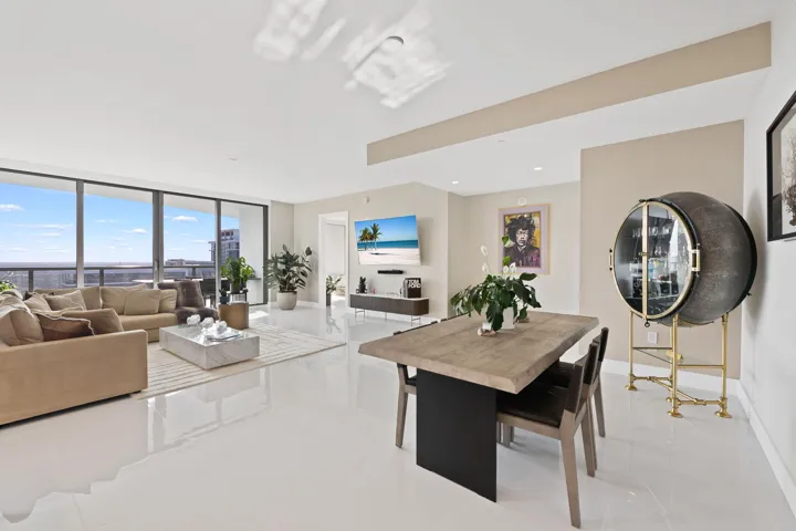 Spacious living area featuring expansive floor-to-ceiling windows, white tile flooring, and recessed lighting