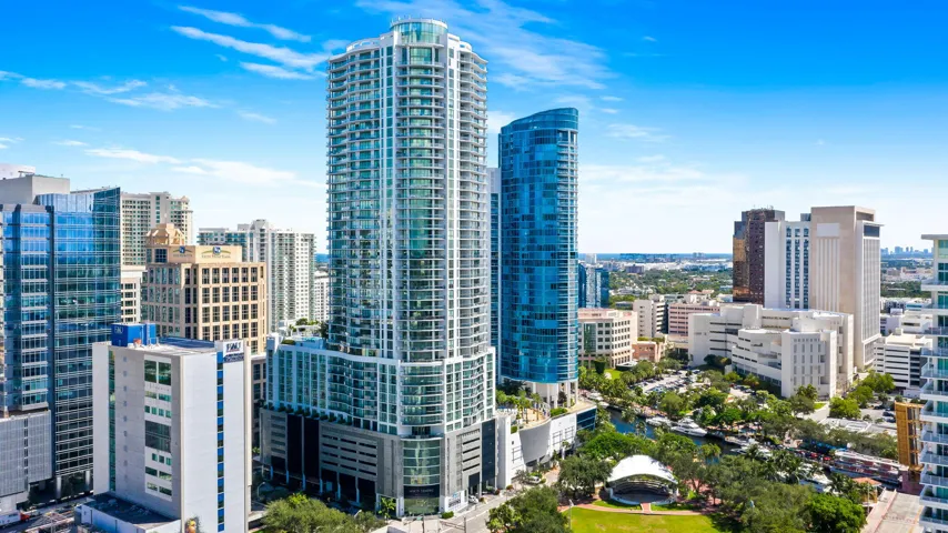 Modern high-rise building featuring a glass and concrete facade, multiple balconies, and a structured parking garage