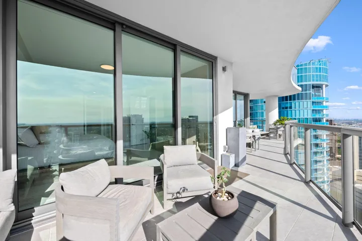 Expansive private balcony featuring glass railings, a curved ceiling, and light-tone tile flooring
