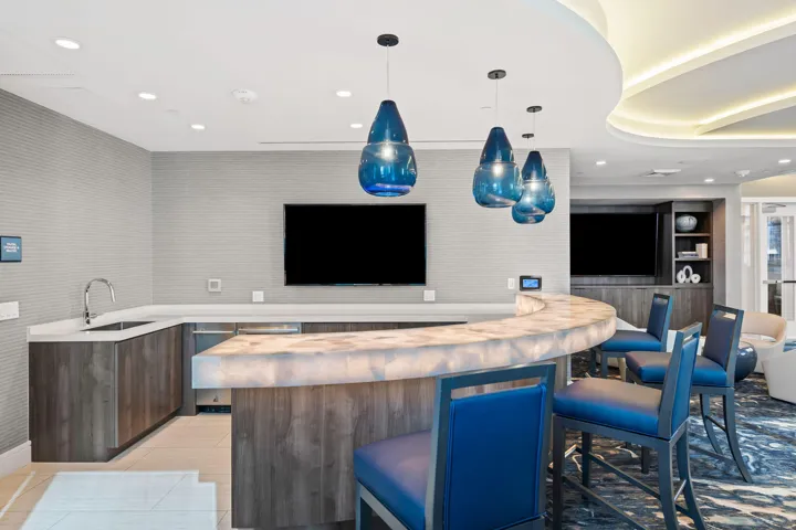 Curved bar with an illuminated countertop, integrated sink, and modern cabinetry