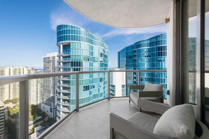 Curved balcony featuring tile flooring and glass railings with metal accents