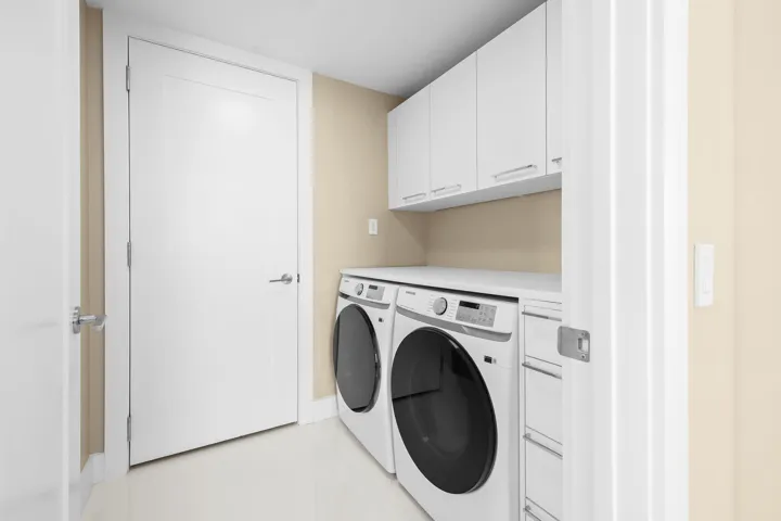 Dedicated laundry space featuring a side-by-side washer and dryer, white cabinetry, a white countertop, and light-toned wall paint