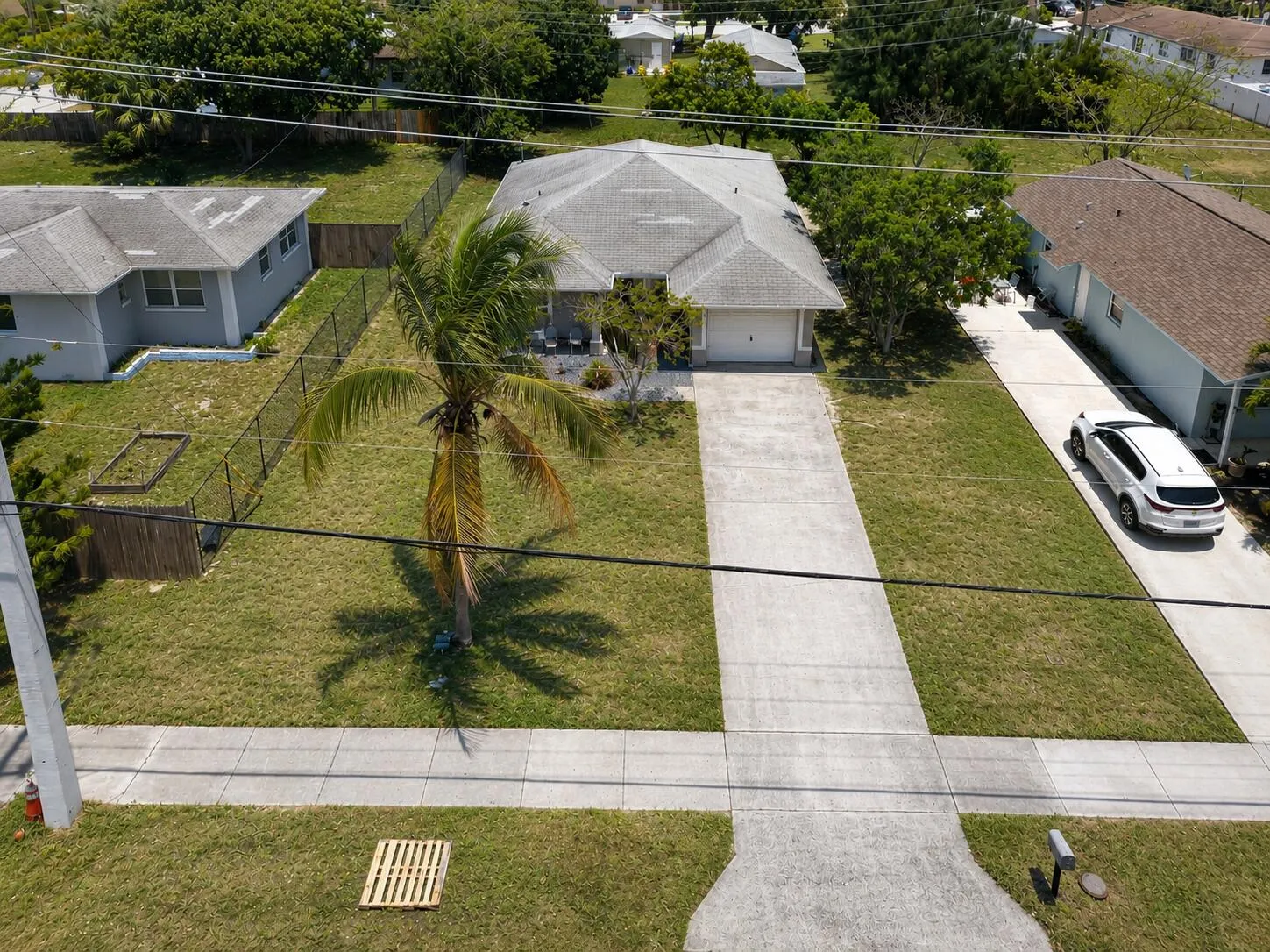 Elevated front view featuring the oversized driveway and mature landscaping