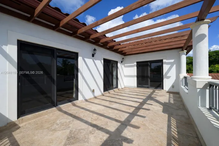second floor terrace with glass doors to primary bedroom, oversized landing and one of the 2nd floor bedrooms. overlooks back yard and pool.