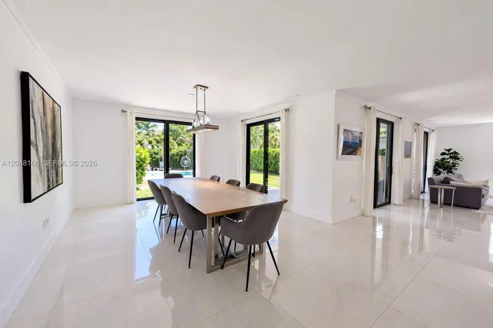 large, naturally-lit dining area with space for guests. floor-to-ceiling doors lead to back yard terrace and pool.