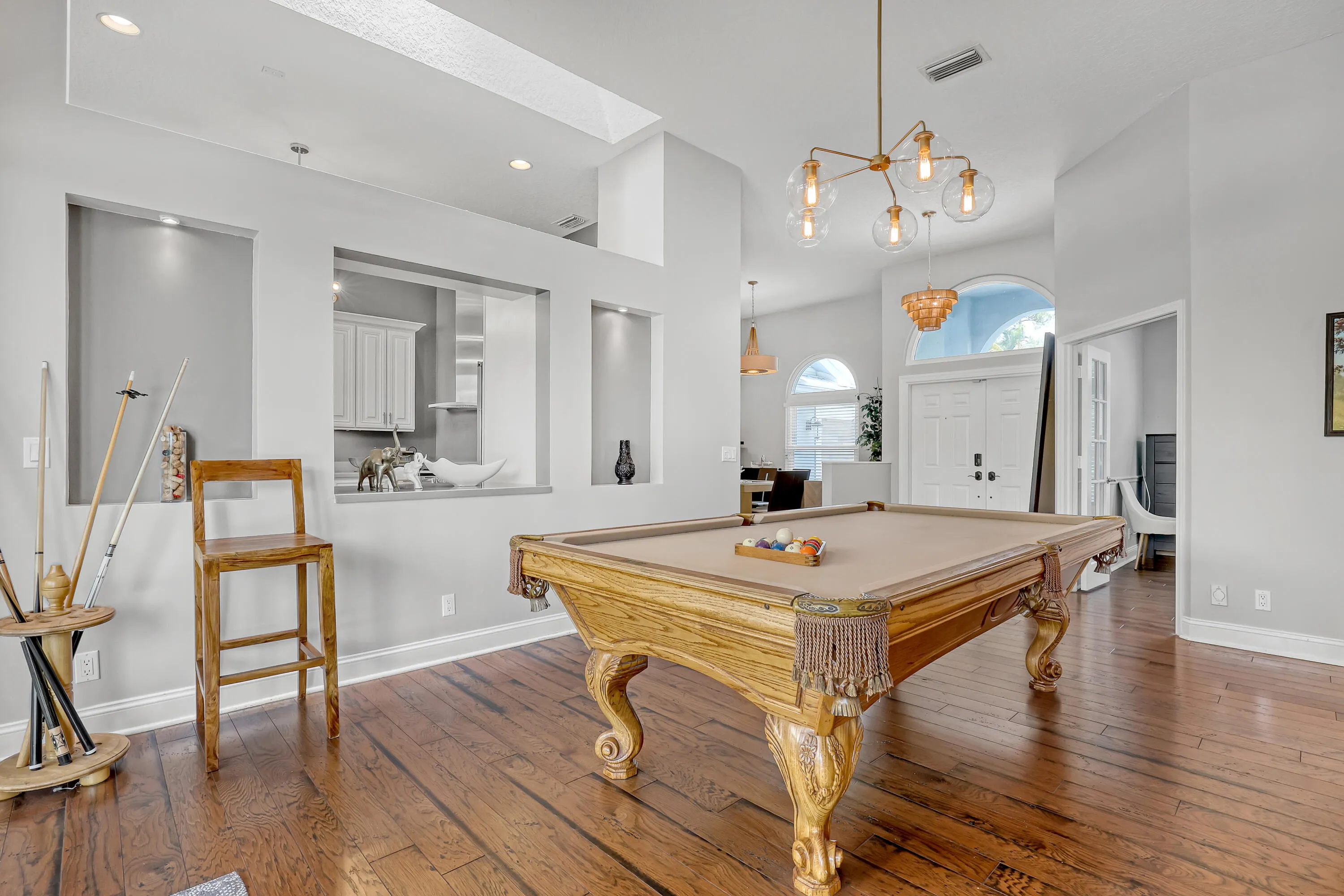 Open-concept entertainment space featuring rich wood-finish flooring, a decorative pool table, and built-in wall niches