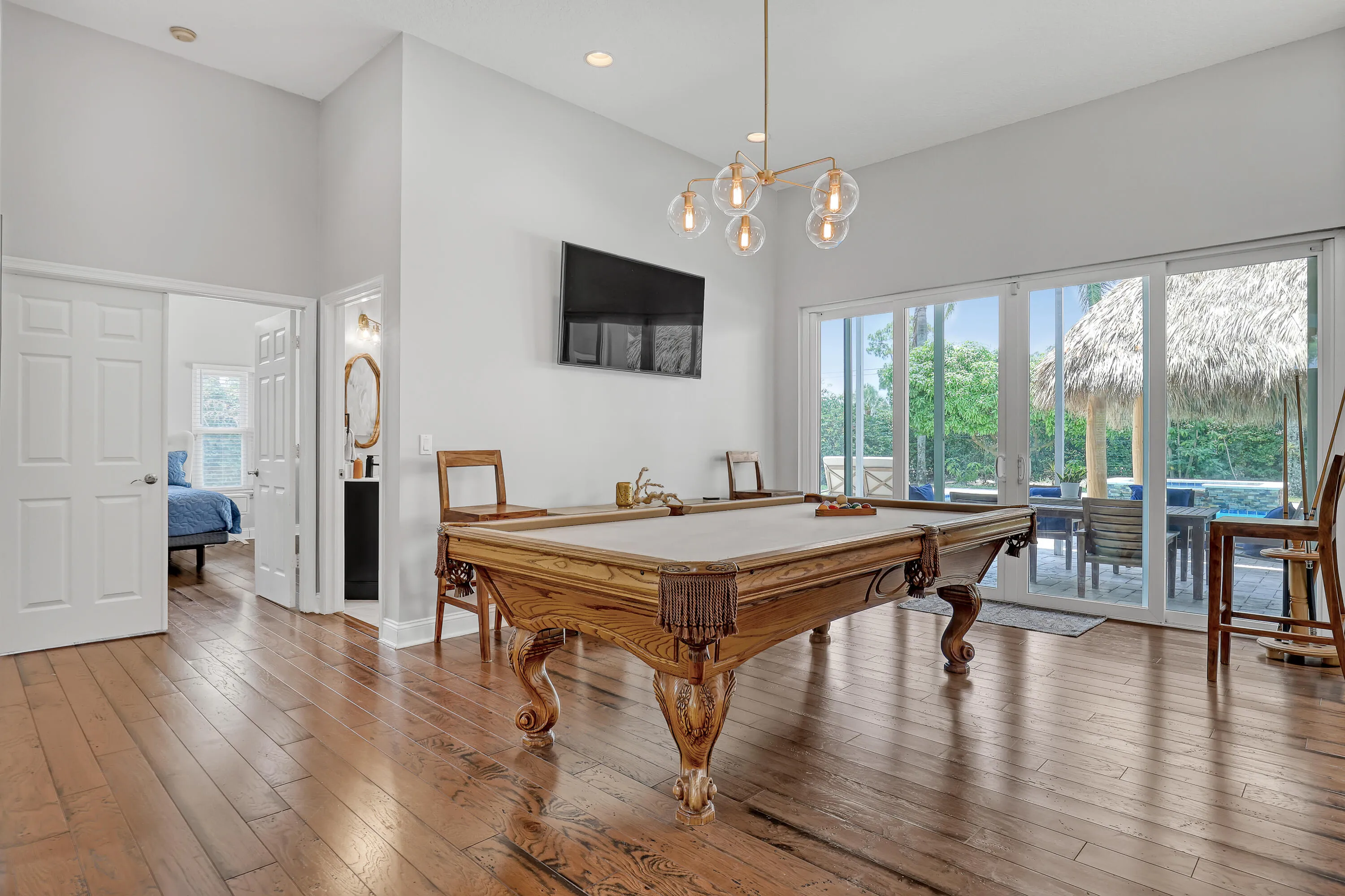 Spacious room featuring wood-finish flooring and a contemporary chandelier above pool table